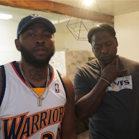 two men standing next to each other in a room