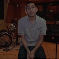 a man sitting in front of a drum set in a recording studio