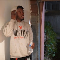 a man in a hoodie leaning against a wall