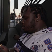 a man is holding a lit cigarette in front of a building