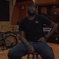a man sitting on a stool in a recording studio