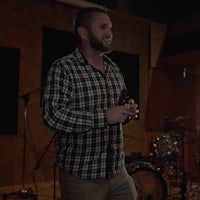 a man standing in front of a microphone in a recording studio